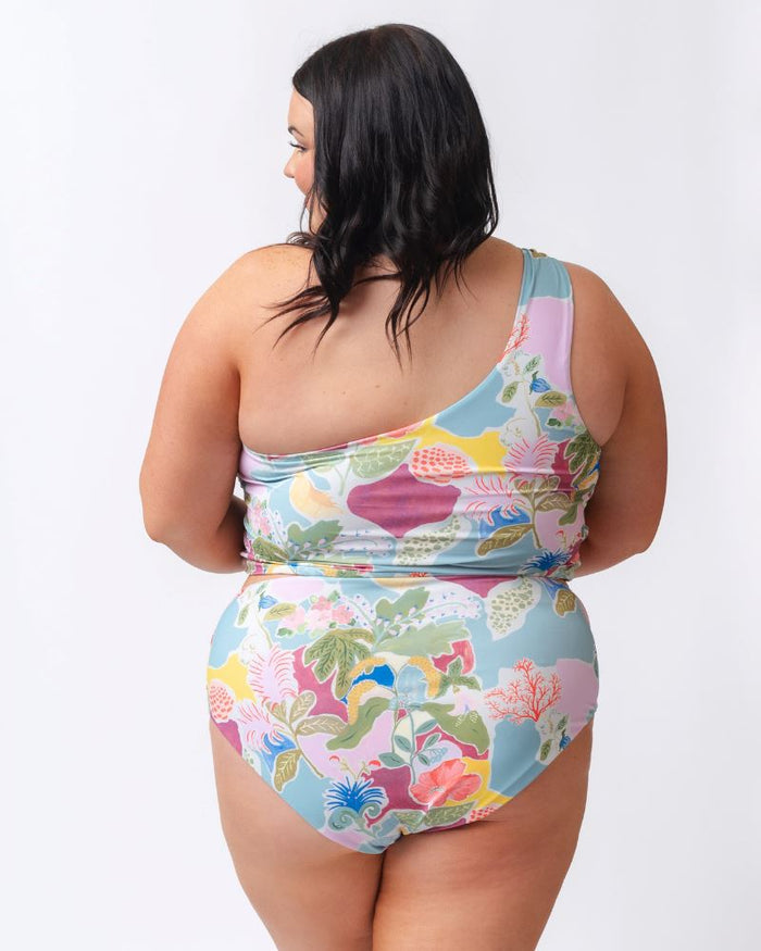 Photo of a woman wearing a colorful seashell inspired high waist swim bottom and a colorful seashell inspired one-shoulder swim crop top- back angle