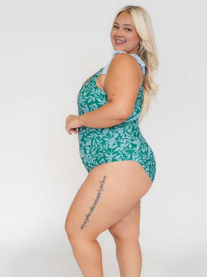Woman wearing a white leaf-patterned one- piece swimsuit on a white background