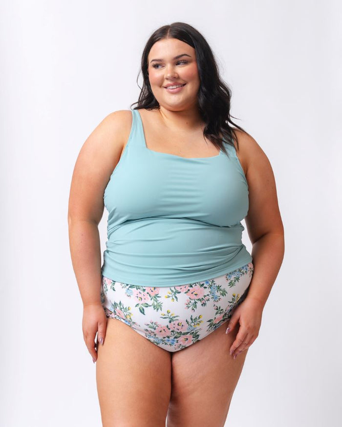 Photo of a woman wearing a light blue square neck swim tankini top and a white and pink floral swim bottom
