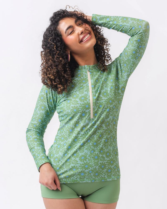 Photo of a woman wearing a green floral long sleeve swim top with light green swim shorts