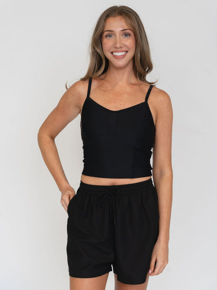Woman wearing a black tank top and black  shorts on a white background