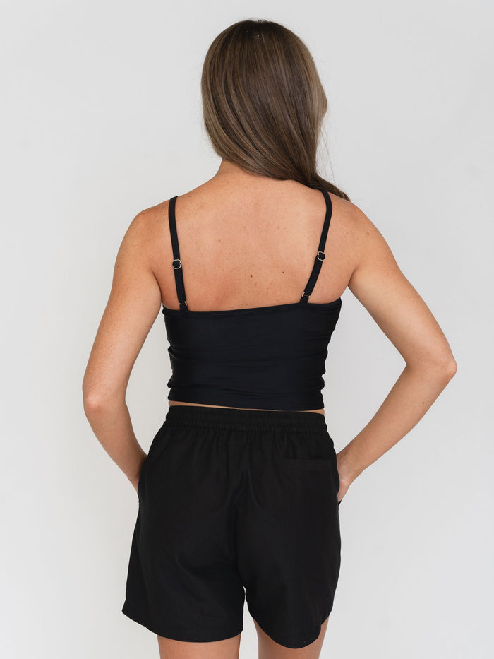 Woman wearing a black tank top and black shorts on a white background