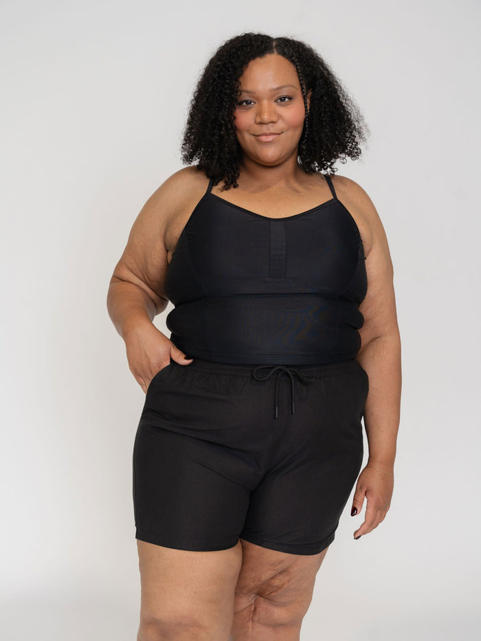 woman wearing a black tank top and black shorts set on a white background