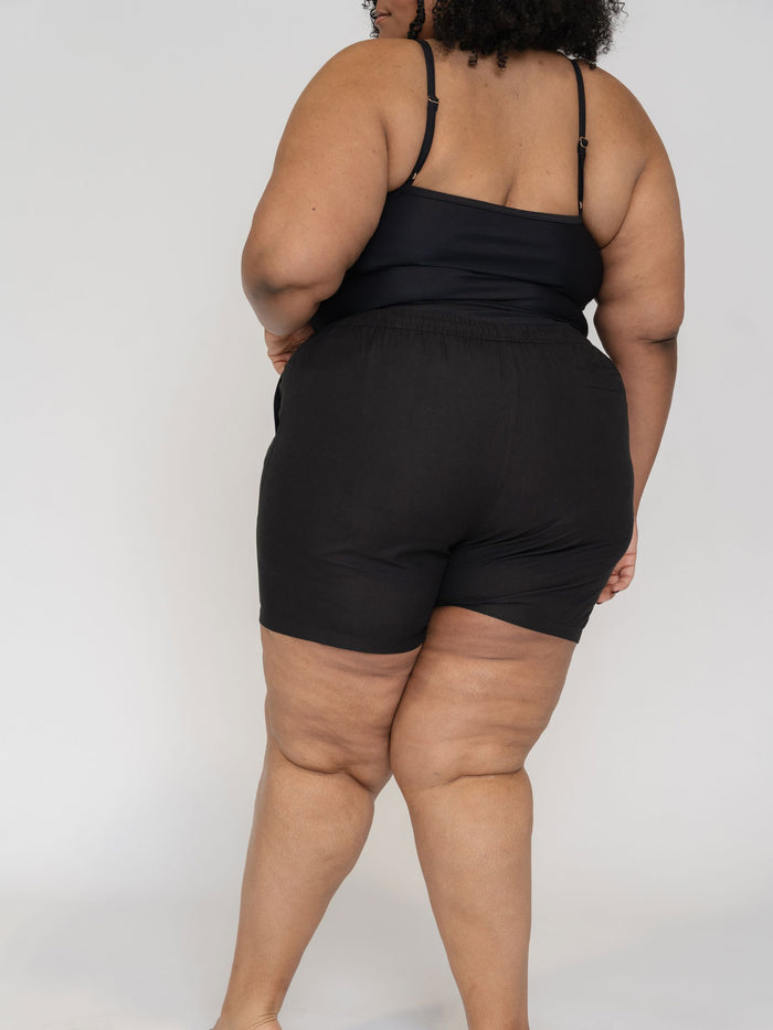 Person wearing a black tank top and black shorts on a white background