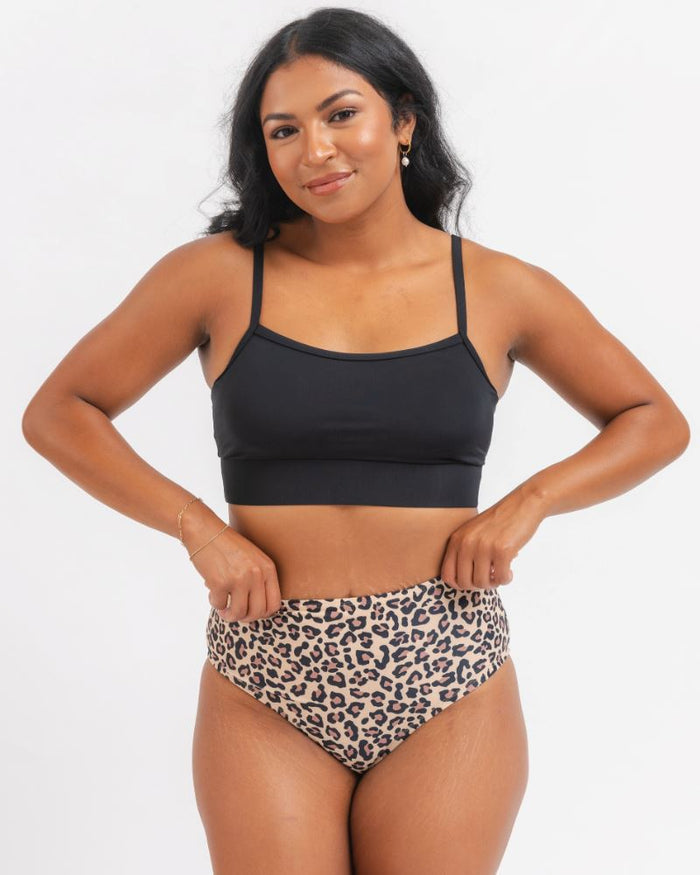 woman wearing a black sports bra and a leopard bikini on a white background