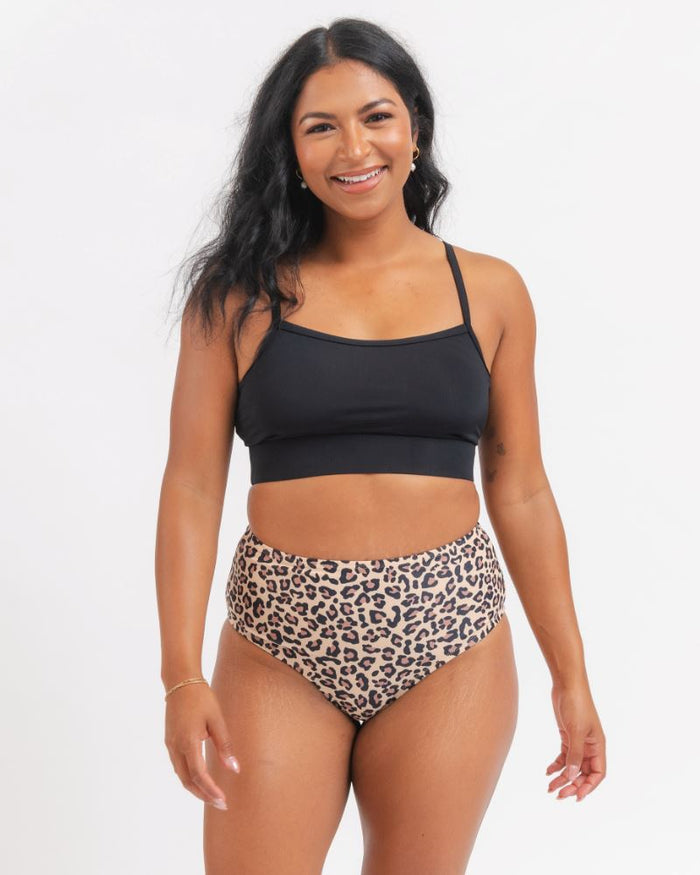 woman wearing a black sports bra and a leopard bikini on a white background