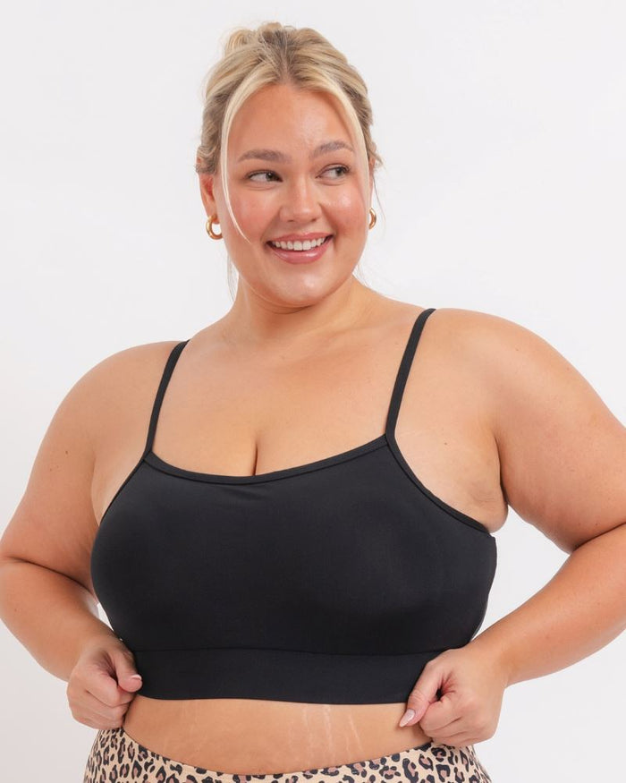 Close up of a woman wearing a black Sports bra and Leopard bikini bottoms on a white background