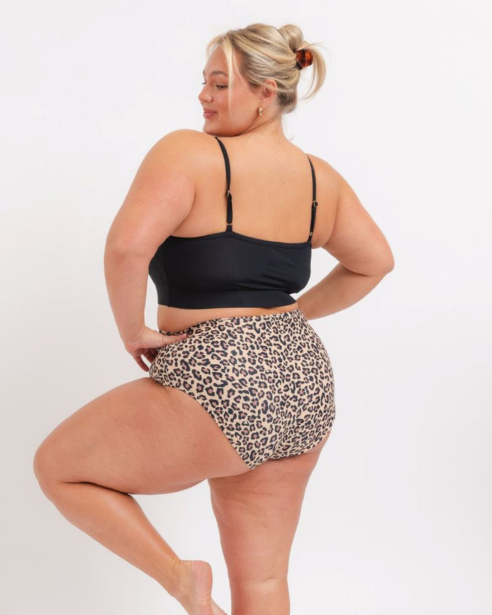 woman in a Black sports bra and a Leopard bikini on a white background. Back view