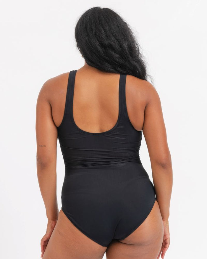 woman in Black knotted one piece on a white Background. Backside view