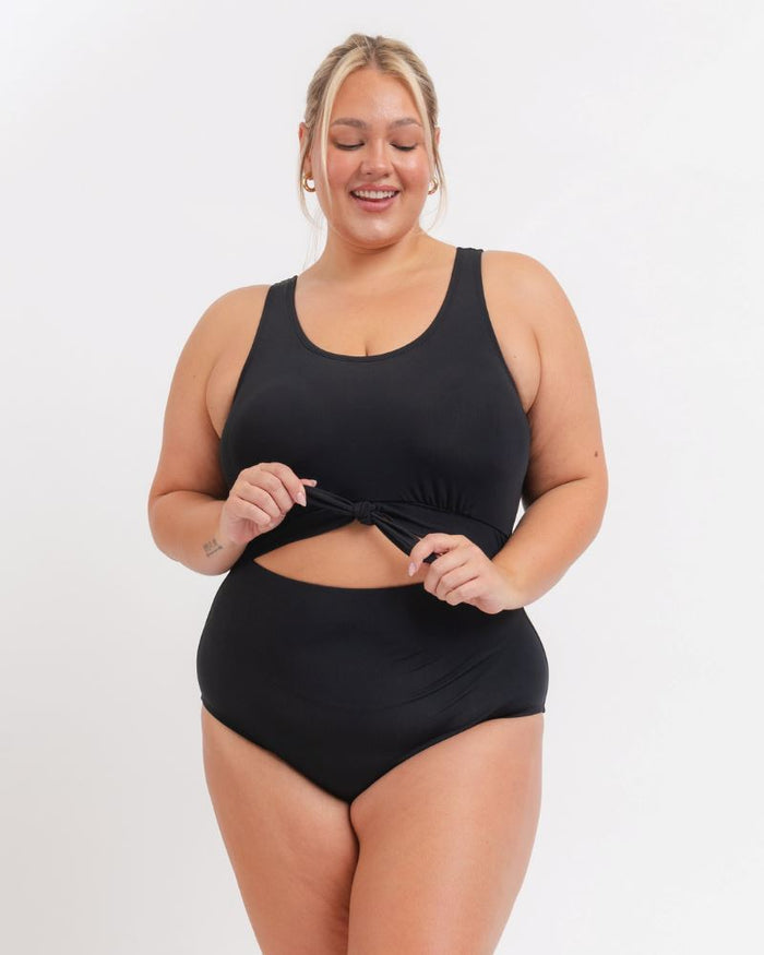 woman wearing a black knotted one piece with a white background