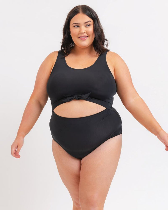 woman wearing a black knotted one piece with a white background