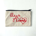 Bless Yer Heart Pencil Bag featuring bold red lettering on a neutral fabric background. Perfect as a Texas themed gift, this stylish and functional pencil case makes a great addition to your collection of Texas Made Gifts. Ideal for souvenirs from Texas or as a Dallas souvenir, it's a must-have for anyone looking for unique Texan gifts.