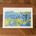 A vibrant BLUEBONNETS Art Print featuring a blue and yellow landscape with longhorn cattle and a skyline, perfect for Texas themed gift enthusiasts. This print serves as a beautiful Texas Made Gift and an ideal souvenir from Texas, showcasing Dallas landmarks, making it a great addition to any collection of Texan gifts.