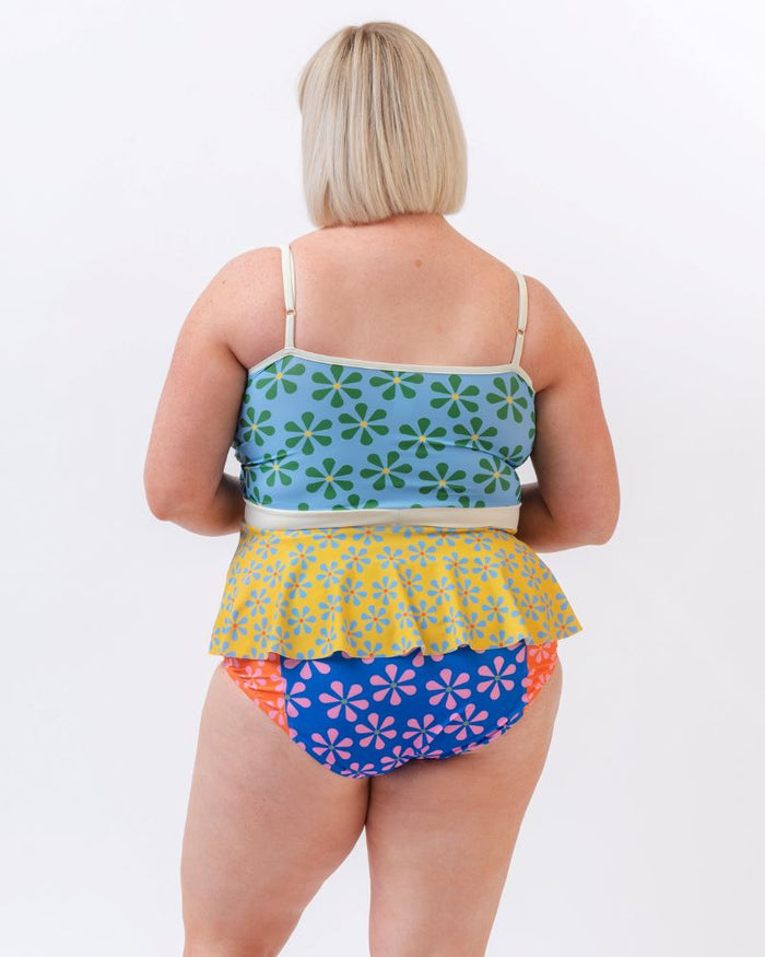 Photo of a woman wearing a multi-colored floral peplum swim top and a multi-colored floral swim bottom- back angle