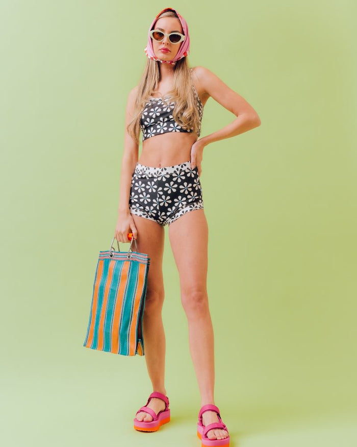Photo of a woman wearing a black and white floral swim short bottom and a black and white floral swim bralette