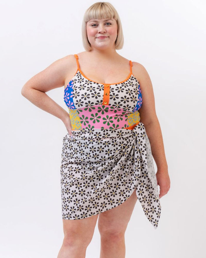 Photo of a woman wearing a black and white floral sarong and a multi colored floral one-piece swimsuit