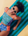 Photo of a woman laying on a beach towel wearing a multi-colored floral square neck swim crop top and a multi-colored floral swim bottom