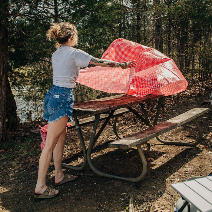 Person Spreading Camco Red White Checkered Tablecloth on Campsite Picnic Table | United RV Parts