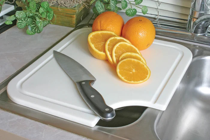 White Camco Sink Mate Cutting Board Over RV Sink - In Use with Orange Slices | United RV Parts
