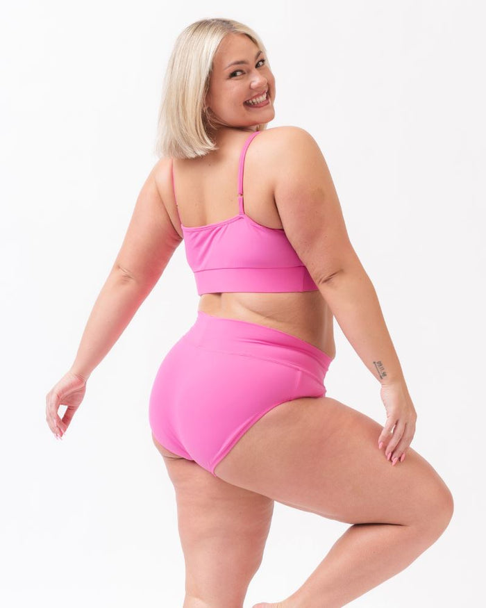 Photo of a woman wearing  dark pink swim bralette and a dark pink swim bottom -side angle