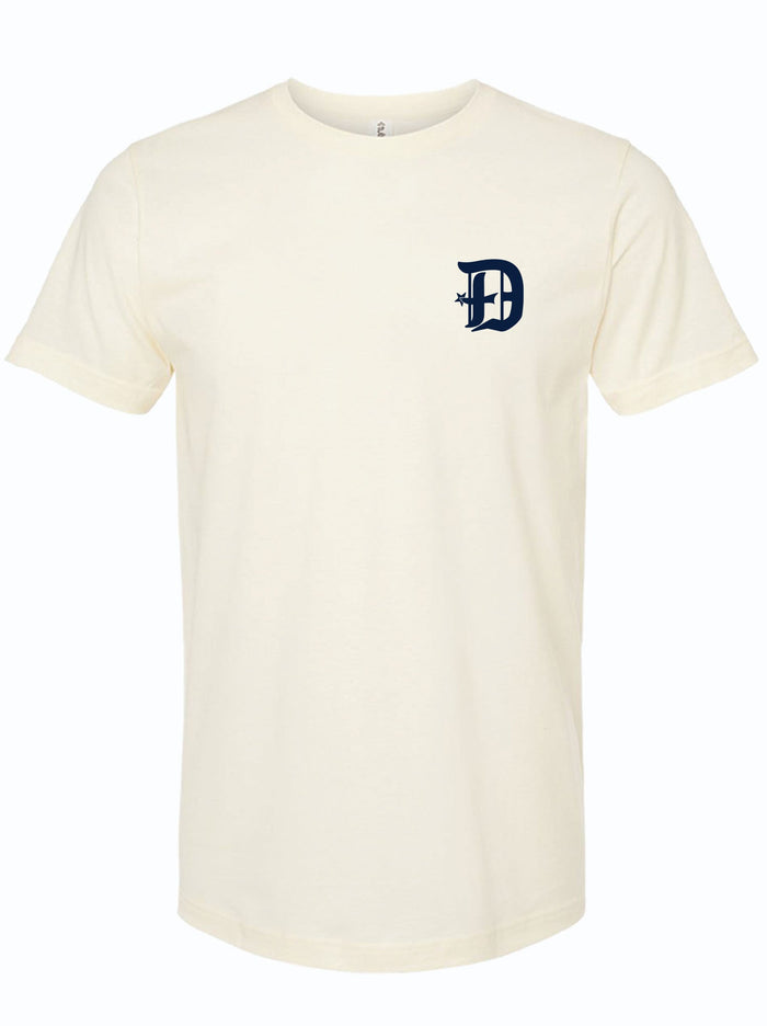 Cream colored tshirt with a D spur logo on the left chest area in dark navy ink.