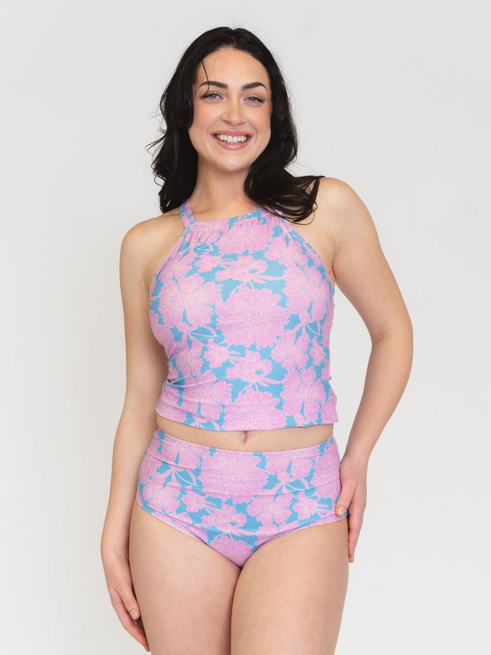 Woman wearing a pink and blue floral two-piece swimsuit on a white background