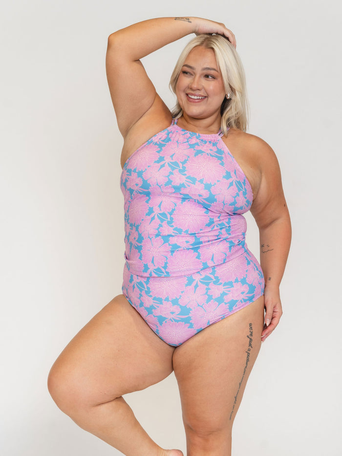 Woman wearing a pink and blue floral swimsuit against a white background