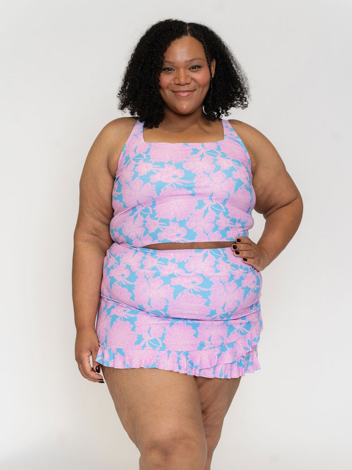 Woman wearing a pink and blue patterned swim dress on a white background