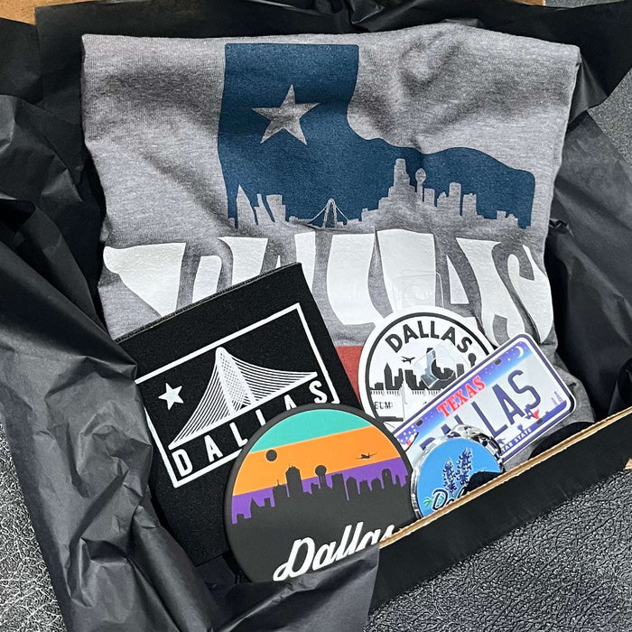 Dallas Gift Box featuring a Bullzerk Dallas Skyline Silhouette t-shirt and an assortment of Dallas-themed small products.