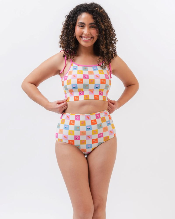 Photo of a woman wearing a multi colored checkered print cropped swim top with multi colored checkered print high waist swim bottoms