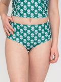 Woman in a Green bikini and matching Top with white floral pattern on a white background