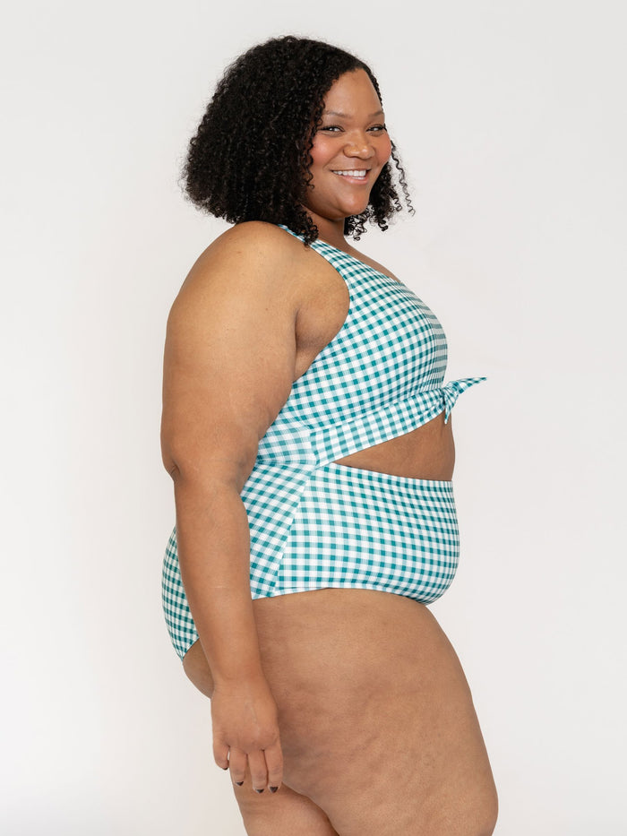 Woman wearing a green and white checkered swimsuit on a plain background
