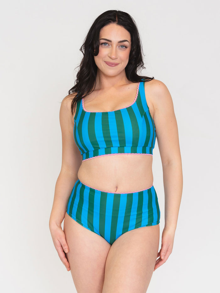 Woman wearing a blue and green striped swimsuit on a white background