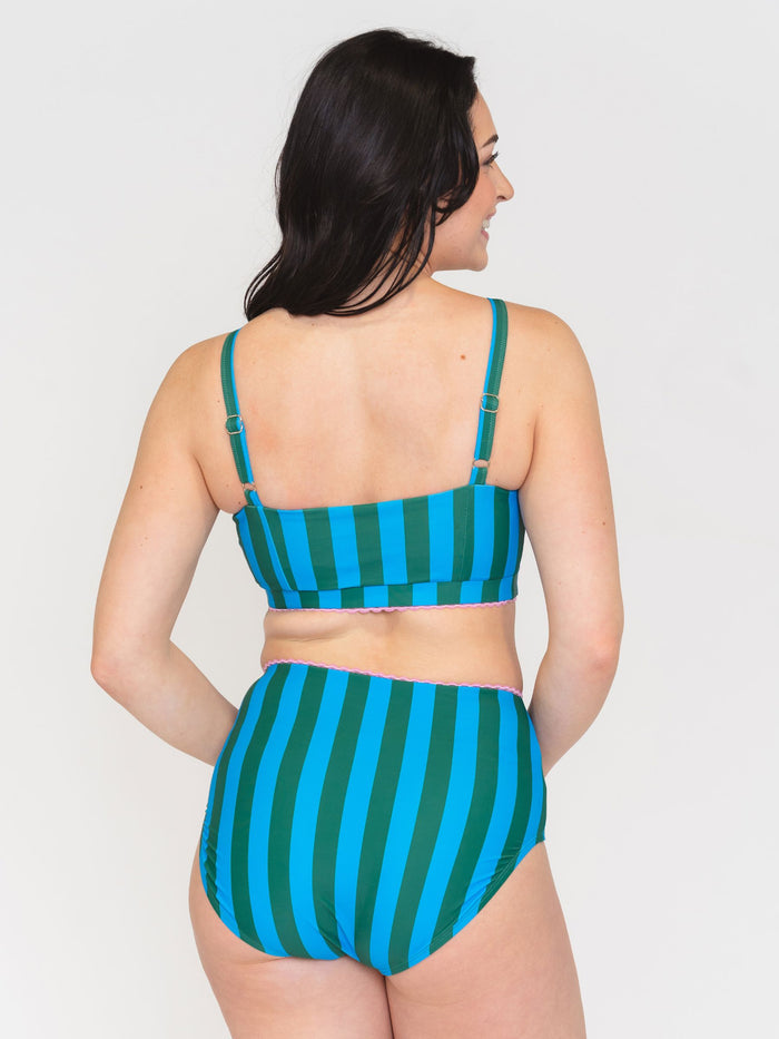 Back view of a woman wearing a green and blue striped bikini set on a white background