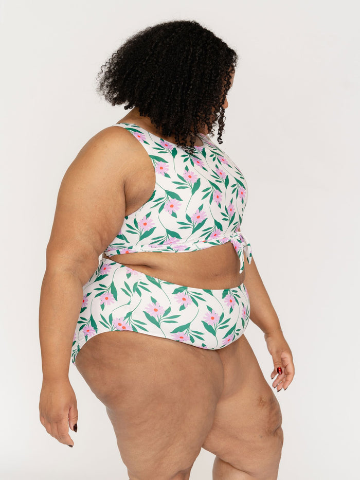 Woman wearing a floral two-piece swimsuit on a plain background