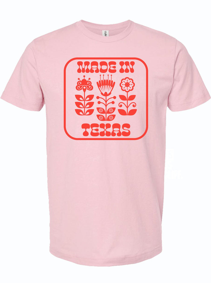 Pink tshirt with a graphic design of red flowers and text reading "Made In Texas" in red letters.