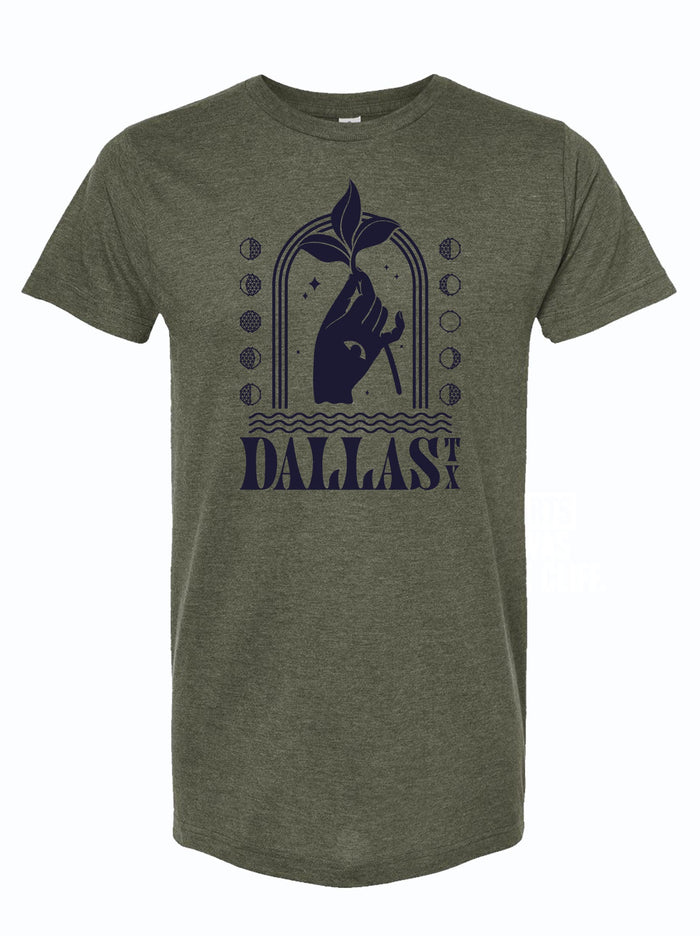 Olive green tshirt that has a graphic design of a hand with an eye on it, holding a sprig of leaves and the text "Dallas TX" underneath it.