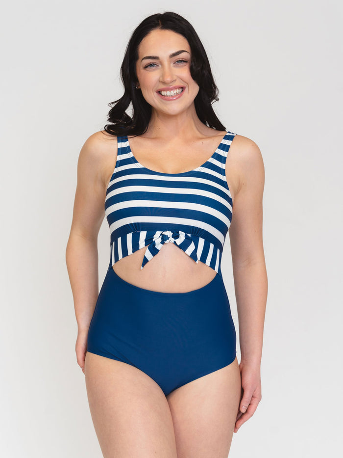 Woman wearing a blue and white striped swimsuit on a plain background