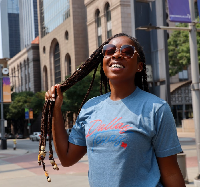 Woman in sunglasses and the Bullzerk Neon Dallas tshirt standing outside in downtown Dallas.