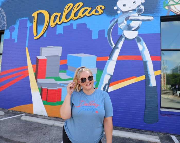 Woman posing in front of a colorful mural, wearing the Bullzerk Neon Dallas tshirt.