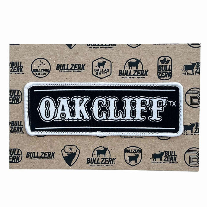 A stylish Oak Cliff Patch featuring bold white lettering on a black background, perfect for decorating jackets or bags. This Texas themed gift showcases quality embroidery and iron-on backing, making it an ideal souvenir from Texas, a great find among Dallas souvenirs and Texan gifts.