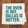 Oven Is Hot Tea Towel featuring the phrase 'THE OVEN IS HOT. DALLAS IS HOTTER.' Perfect for adding a touch of humor to your kitchen, this Texas themed gift makes an ideal souvenir from Texas and is perfect for anyone looking for Texan gifts or a Dallas souvenir.