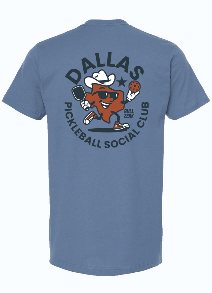 Back view of a slate blue tshirt featuring a graphic design of a Texas-shaped character wearing sunglasses and a cowboy hat playing pickleball. The character is surrounded by a circle of text reading "DALLAS PICKLEBALL SOCIAL CLUB" in navy letters.