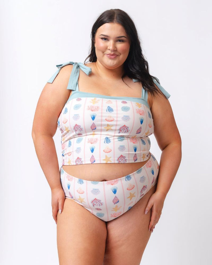 Photo of a woman wearing a seashell striped shoulder-tie swim crop top and a shell striped high waist swim bottom
