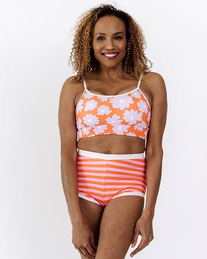 Photo of a woman wearing a Sherbet stripe retro swim short bottom and a Daphne floral swim bralette