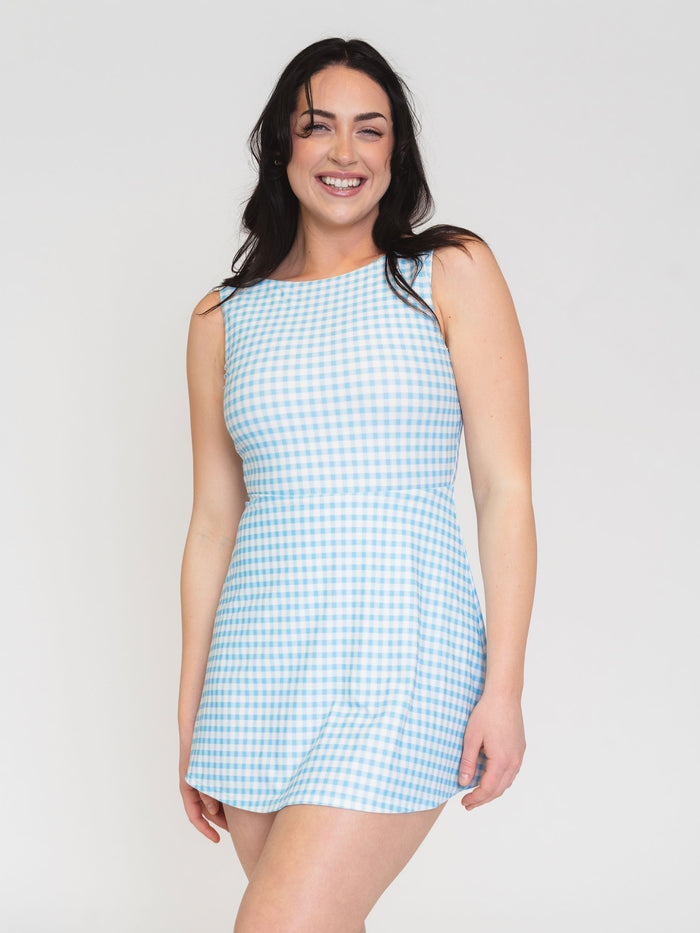 Woman wearing a light blue checkered dress against a plain background