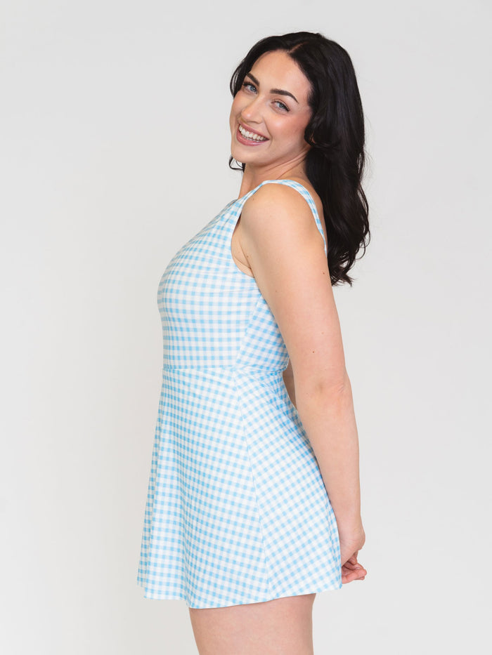 Side view of a woman wearing a light blue checkered swim dress against a white background