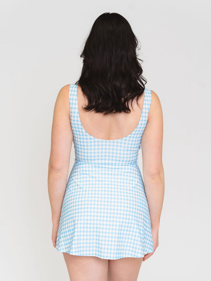 Back View of a woman wearing a blue and white checkered swim dress against a white background