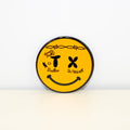 Circular, black and yellow magnet with Smiley Face design.