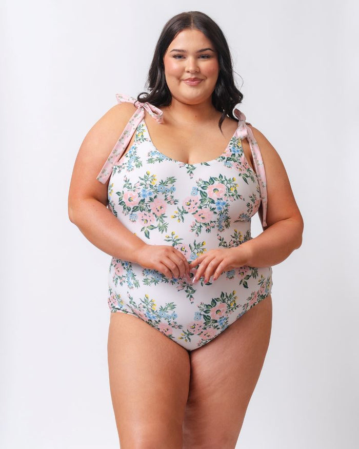 Photo of a woman wearing a pink and white floral one piece swimsuit